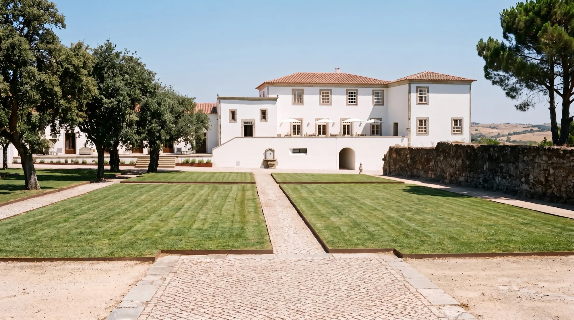 White manor house behind a lawn courtyard with a cobbled path
