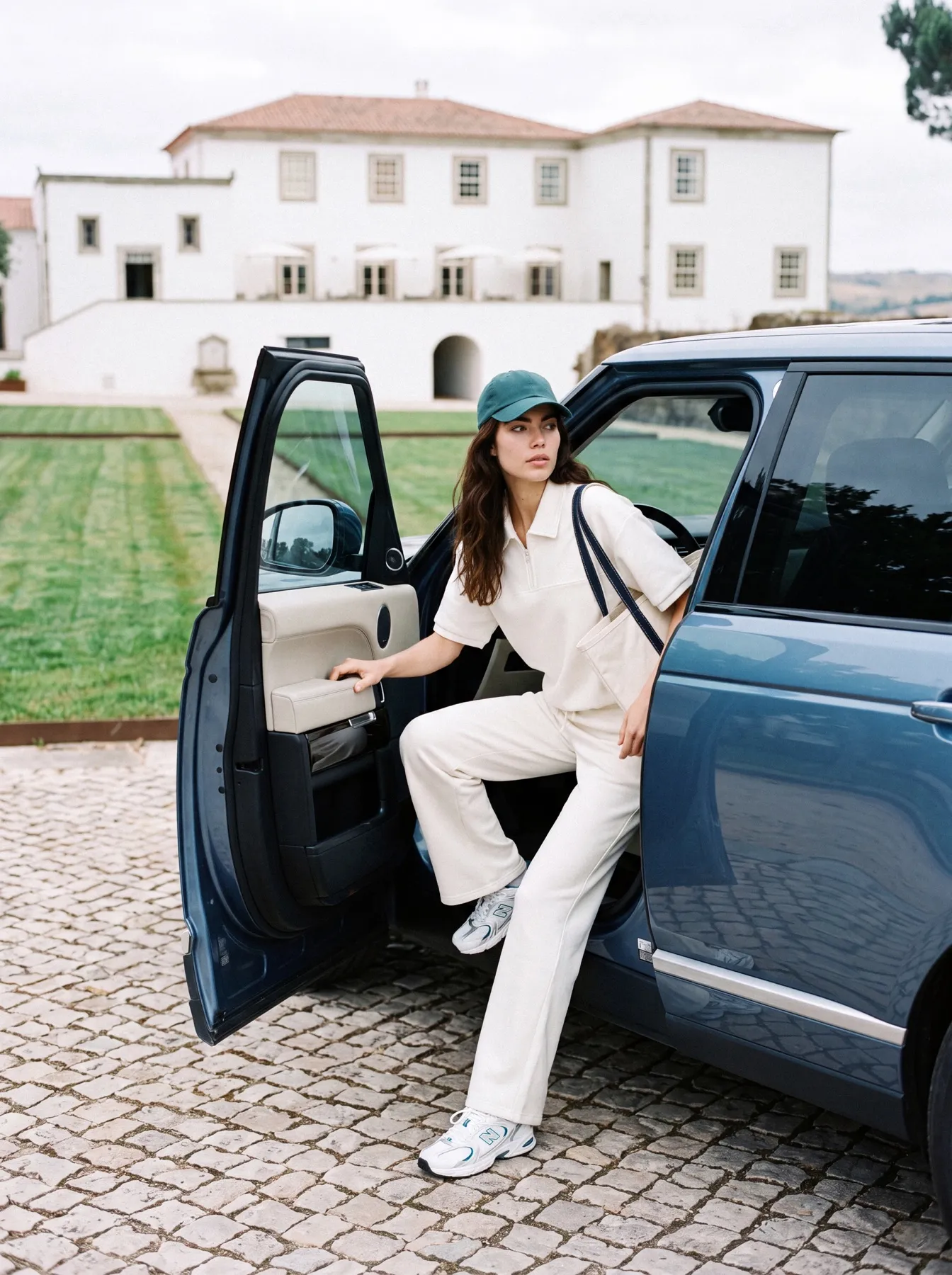 Model stepping out of a blue car parked in front of the house